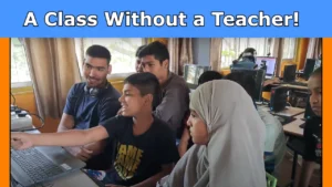 Students are sitting in a classroom while a young peer mentor leads a session using a computer.