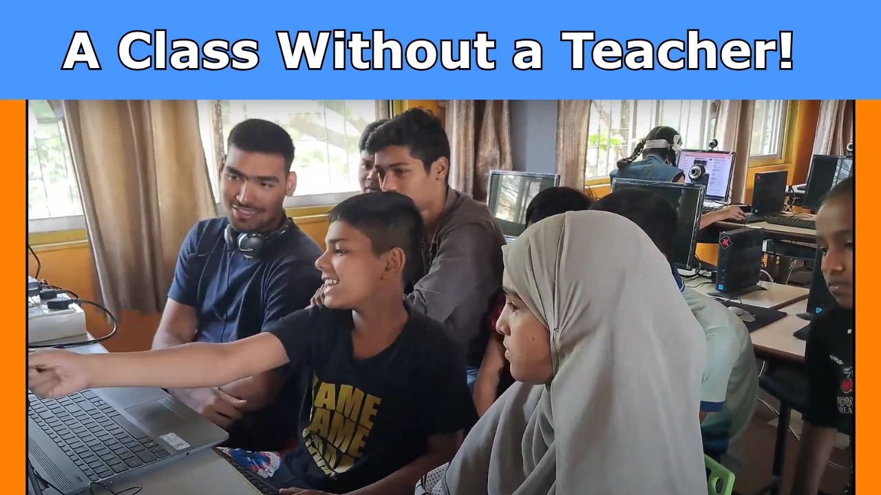Students are sitting in a classroom while a young peer mentor leads a session using a computer.
