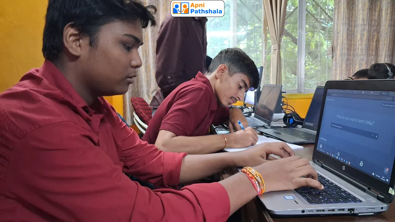 A student at Apni Pathshala using a laptop for digital learning while another student takes handwritten notes, promoting blended self-directed learning.