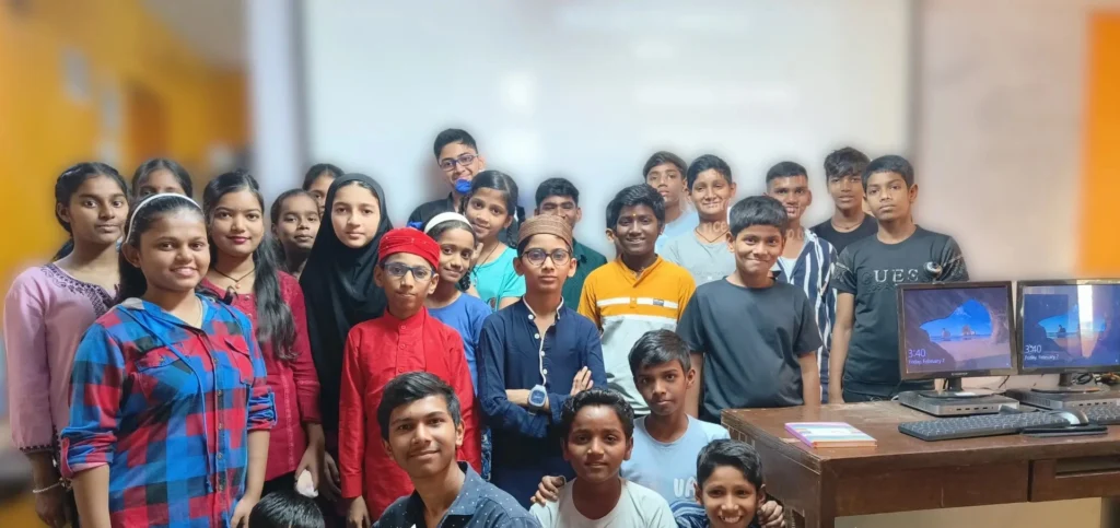 Group of students in a digital learning classroom with computers, smiling together
