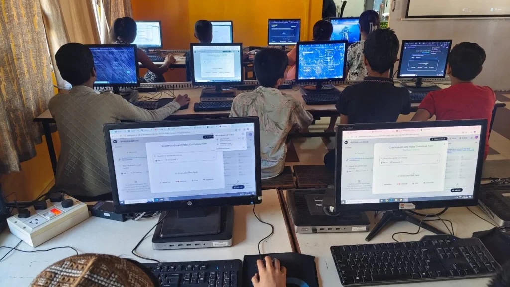 “Students learning computer skills in a digital classroom with desktop computers”